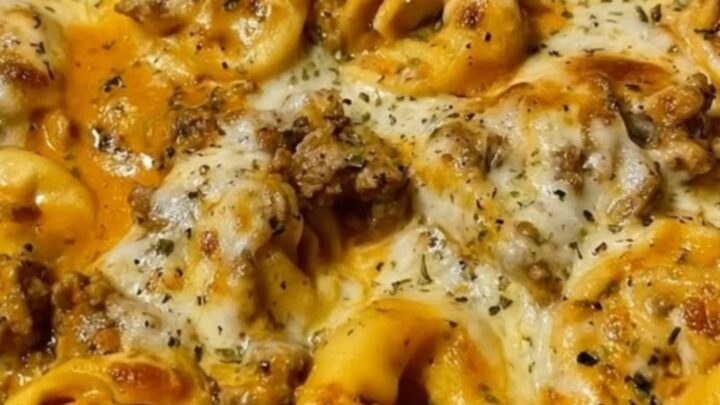 A bubbly cast iron skillet filled with creamy beef and cheese tortellini, topped with melted mozzarella.