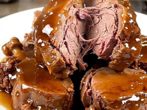 A close-up of tender, glazed veal tendrons on a white plate with a rich, glossy honey balsamic sauce.