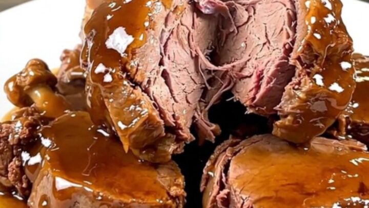A close-up of tender, glazed veal tendrons on a white plate with a rich, glossy honey balsamic sauce.