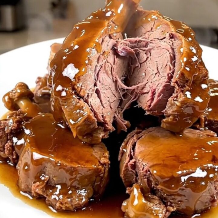 A close-up of tender, glazed veal tendrons on a white plate with a rich, glossy honey balsamic sauce.