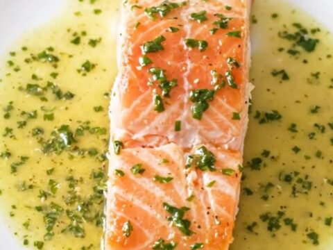 A close-up of a perfectly cooked salmon fillet covered in a creamy white wine and sorrel sauce.
