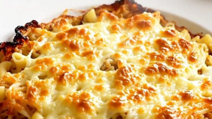 A close-up of a steaming bowl of creamy macaroni pasta with melted Comté cheese and diced ham.