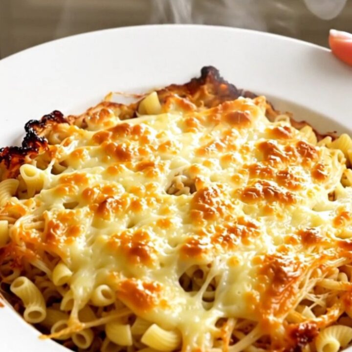 A close-up of a steaming bowl of creamy macaroni pasta with melted Comté cheese and diced ham.