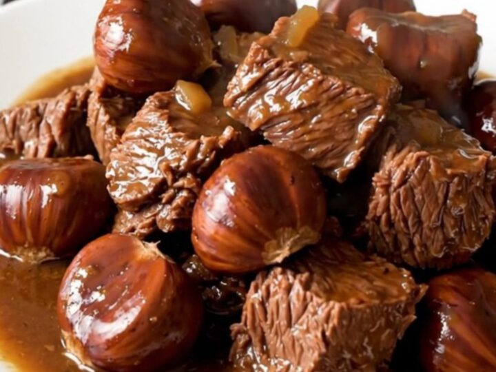 A close-up of a bowl filled with rich beef and chestnut stew, featuring glossy gravy and tender meat chunks.