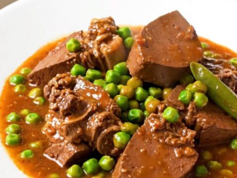 A close-up of a steaming bowl of Veal Marengo featuring tender meat, bright orange carrots