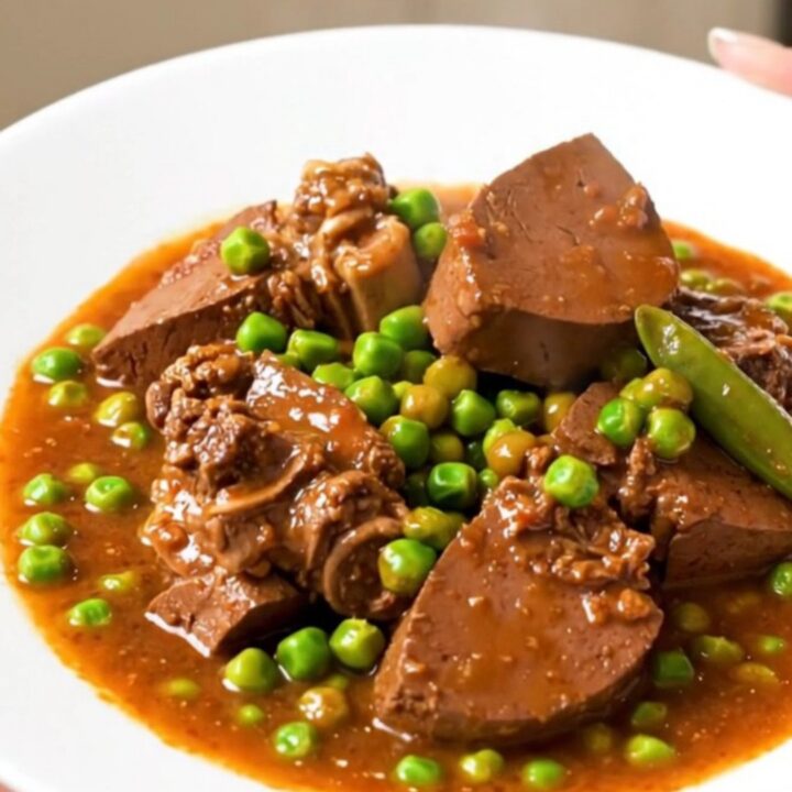 A close-up of a steaming bowl of Veal Marengo featuring tender meat, bright orange carrots