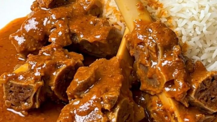 A close-up of a bowl filled with lamb and sweet potato mafé in a rich, creamy peanut sauce.