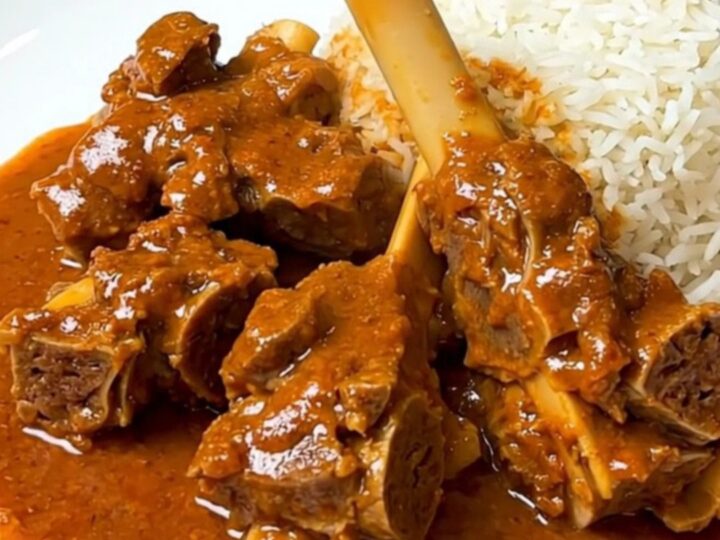 A close-up of a bowl filled with lamb and sweet potato mafé in a rich, creamy peanut sauce.