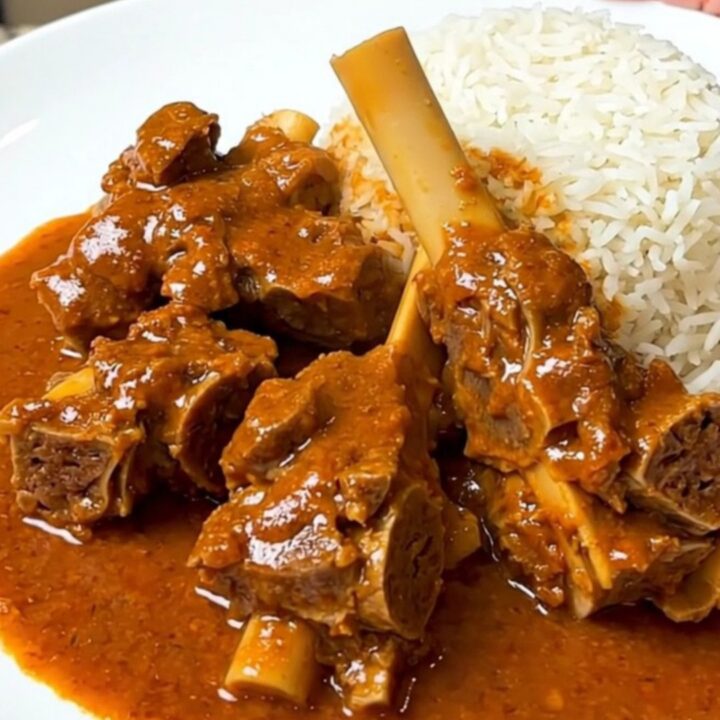 A close-up of a bowl filled with lamb and sweet potato mafé in a rich, creamy peanut sauce.