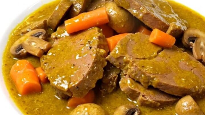 A close-up of a steaming bowl of coconut curry veal blanquette topped with fresh herbs.