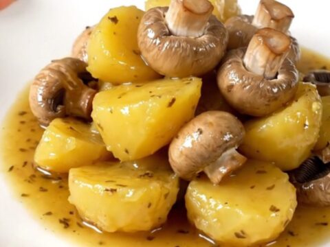 A close-up of tender, glossy melting potatoes and halved button mushrooms in a slow cooker.
