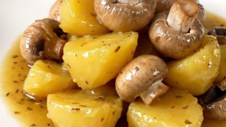 A close-up of tender, glossy melting potatoes and halved button mushrooms in a slow cooker.