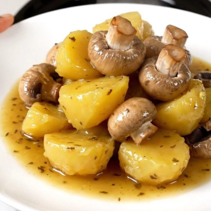 A close-up of tender, glossy melting potatoes and halved button mushrooms in a slow cooker.