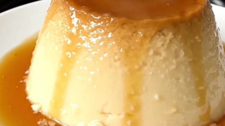 A finished coconut flan with a glossy caramel topping on a white plate.