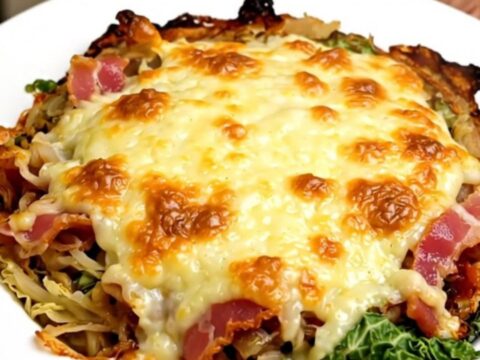 A slow cooker filled with creamy savoy cabbage, bacon, and melted Cantal cheese on a quartz countertop.