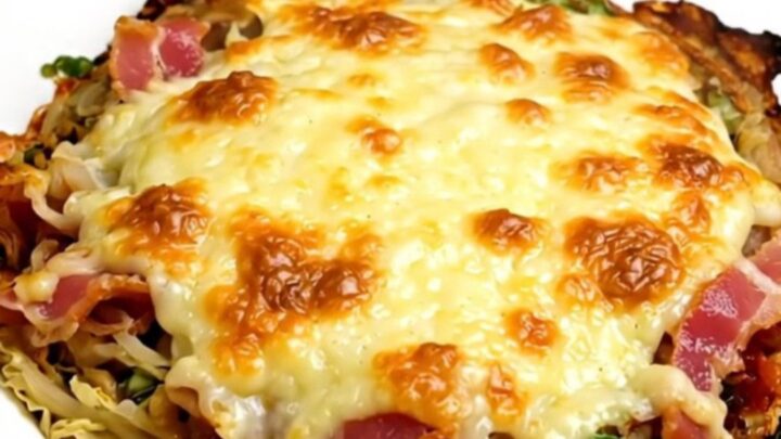 A slow cooker filled with creamy savoy cabbage, bacon, and melted Cantal cheese on a quartz countertop.