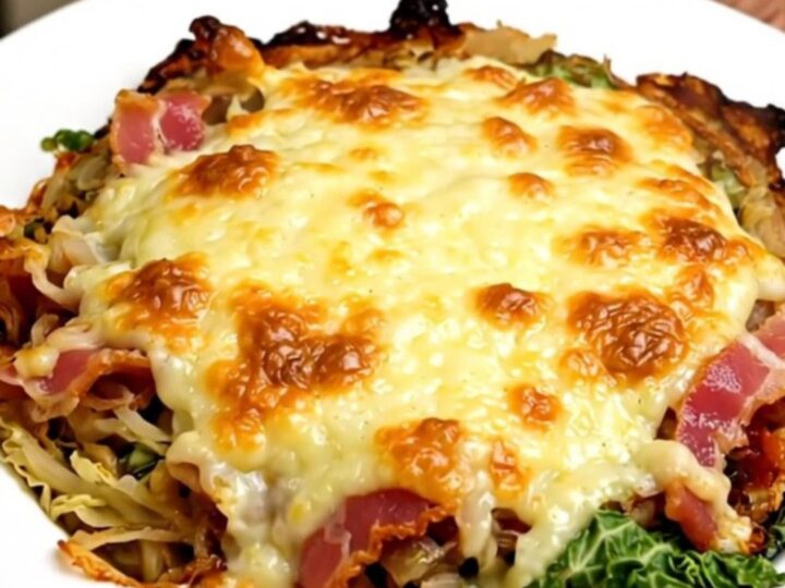 A slow cooker filled with creamy savoy cabbage, bacon, and melted Cantal cheese on a quartz countertop.
