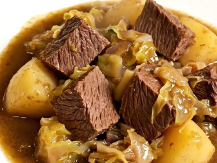 A bowl of slow cooker beef and cabbage stew with tender meat and vegetables in a savory broth.