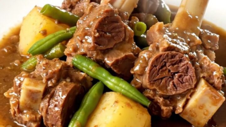 A rustic slow cooker lamb navarin with tender chunks of meat, potatoes, and green beans in a savory broth.