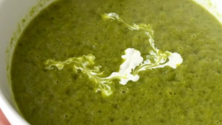 A vibrant green pea and leek velouté in a white bowl with a cream swirl.