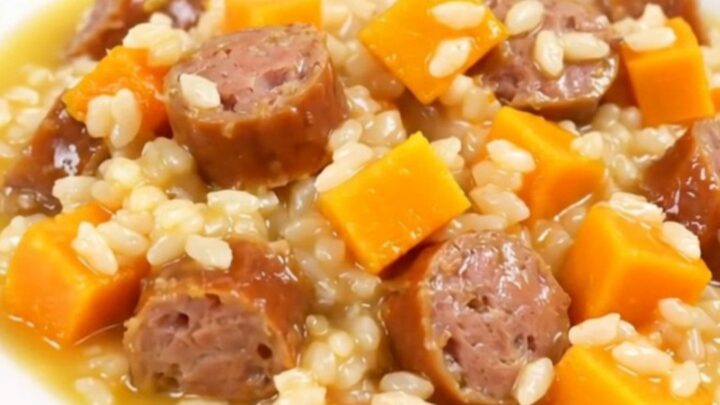A top-down view of a black slow cooker insert filled with raw sausage, butternut squash