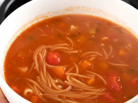A rustic tomato and vermicelli soup in a slow cooker on a bright kitchen counter.