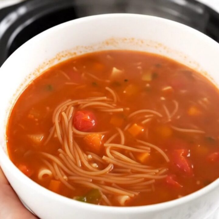 A rustic tomato and vermicelli soup in a slow cooker on a bright kitchen counter.