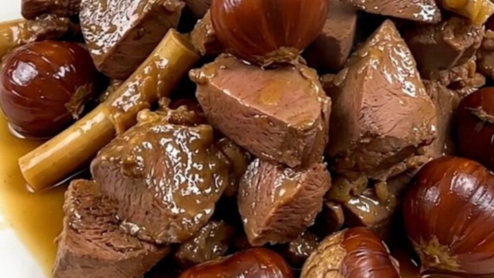 A close-up view of tender braised veal tendrons and whole chestnuts served on a white plate.