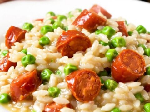 A close-up of creamy chorizo and pea risotto in a black slow cooker insert.