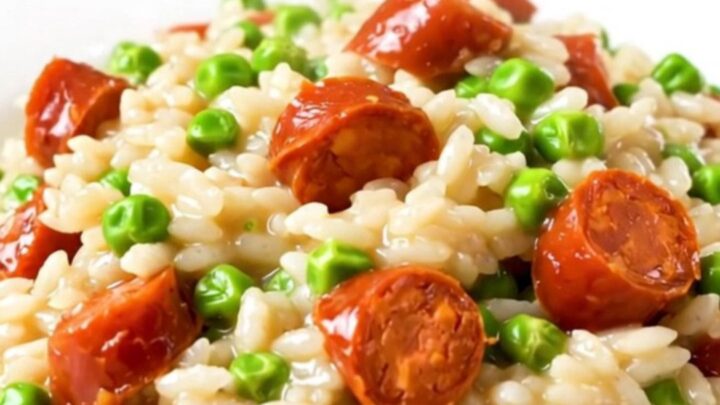 A close-up of creamy chorizo and pea risotto in a black slow cooker insert.