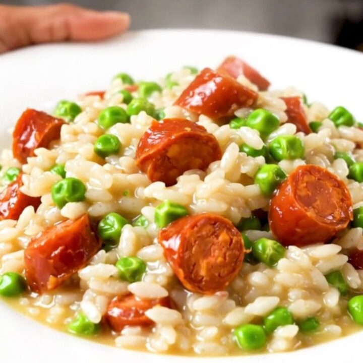 A close-up of creamy chorizo and pea risotto in a black slow cooker insert.