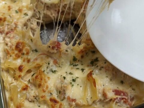 A close-up of a creamy chicken spaghetti lasagna bake with a golden brown cheese crust.