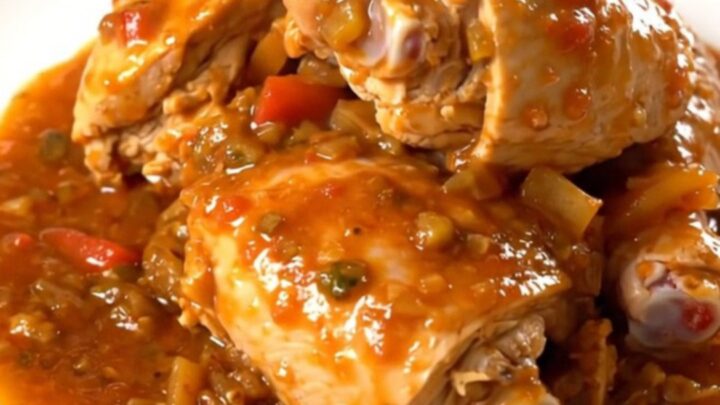 A white plate filled with slow cooker massale chicken, potatoes, and onions in a rich tomato sauce.