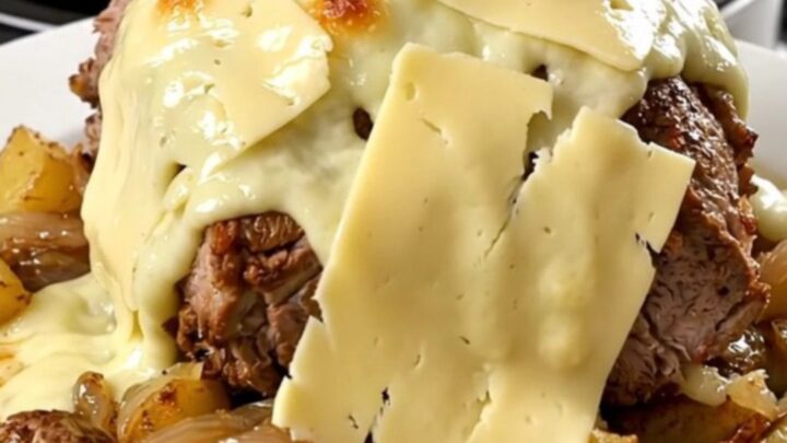A rustic slow cooker pork roast topped with melted Reblochon cheese and potatoes in a black slow cooker.