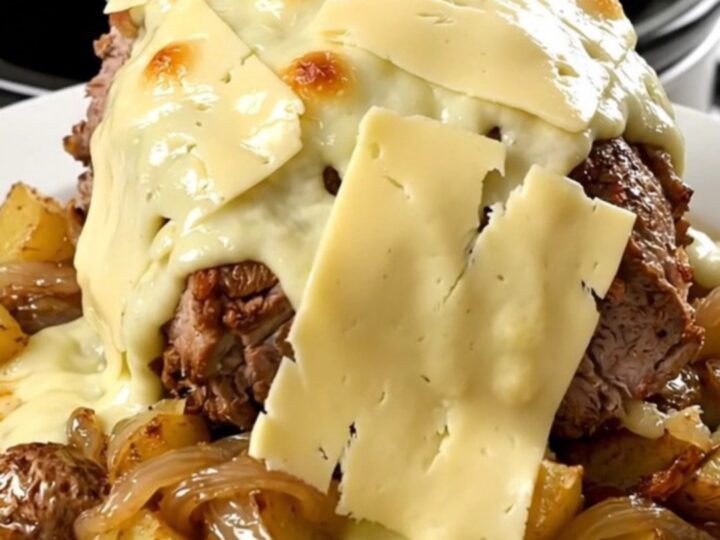 A rustic slow cooker pork roast topped with melted Reblochon cheese and potatoes in a black slow cooker.
