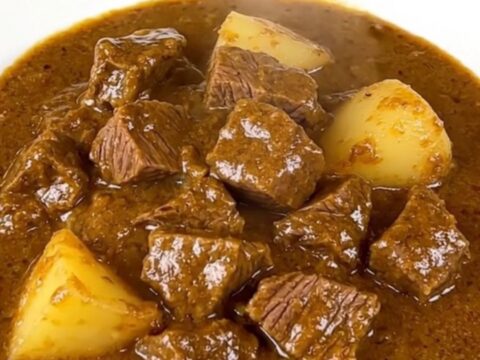A close-up view of the finished beef Massaman curry in a slow cooker insert.