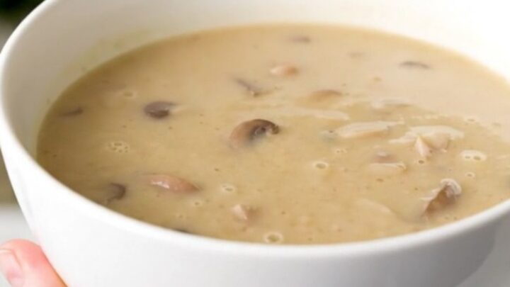 A white bowl filled with creamy, velvety wild mushroom velouté, showcasing its smooth, glossy texture and earthy tones.