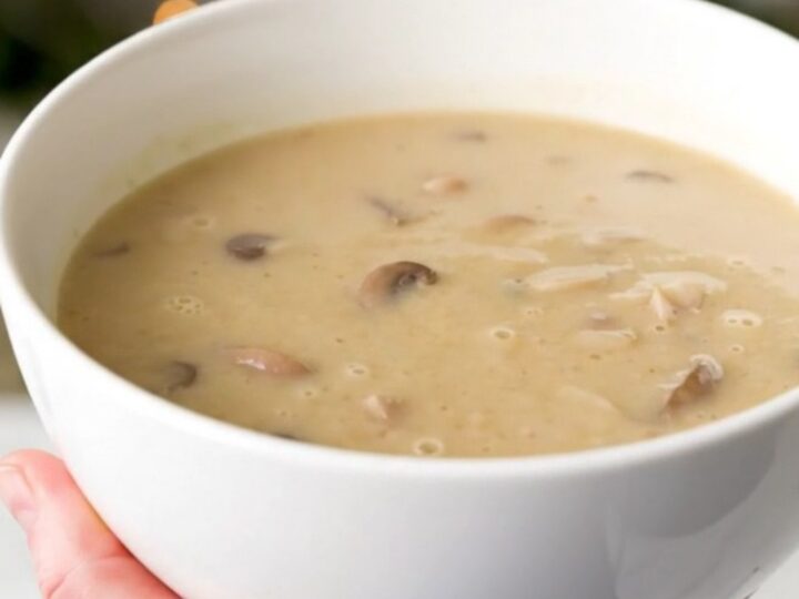 A white bowl filled with creamy, velvety wild mushroom velouté, showcasing its smooth, glossy texture and earthy tones.