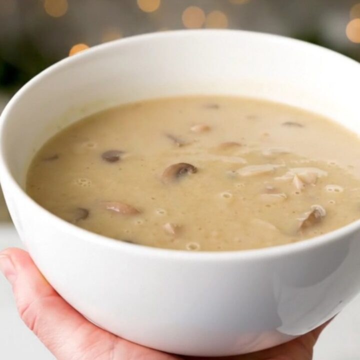 A white bowl filled with creamy, velvety wild mushroom velouté, showcasing its smooth, glossy texture and earthy tones.