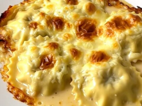 A close-up view of the creamy slow cooker Dauphiné ravioles and mushroom gratin in a white dish.
