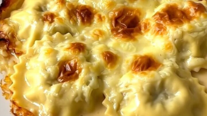 A close-up view of the creamy slow cooker Dauphiné ravioles and mushroom gratin in a white dish.