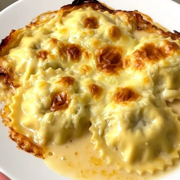A close-up view of the creamy slow cooker Dauphiné ravioles and mushroom gratin in a white dish.