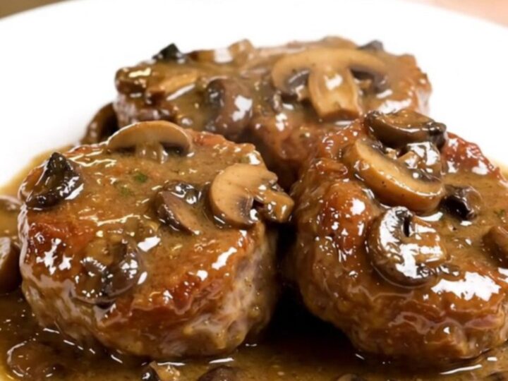 A plate of tender veal paupiettes smothered in a creamy mushroom sauce on a white plate.