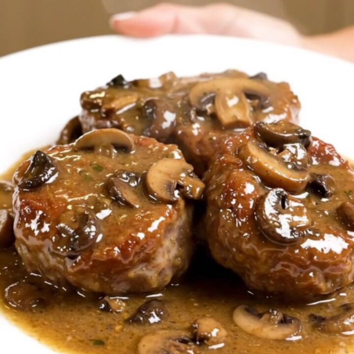 A plate of tender veal paupiettes smothered in a creamy mushroom sauce on a white plate.