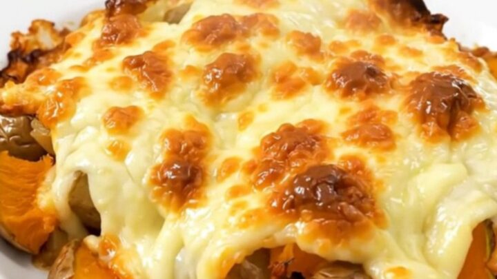 A close-up of a steaming, cheesy red kuri squash and potato gratin served on a plain white plate.