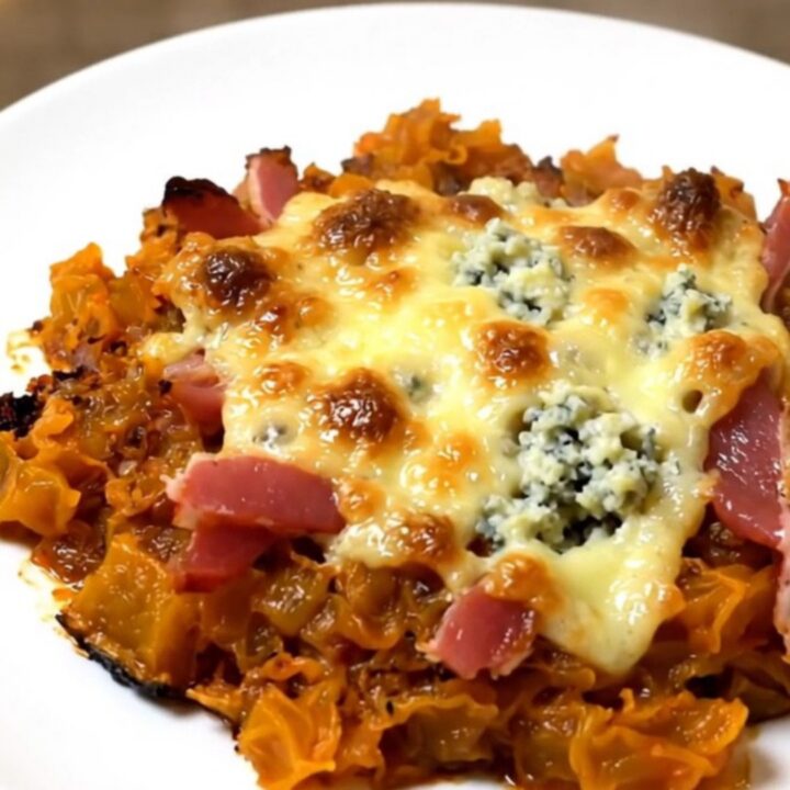 A top-down view of a slow cooker filled with bacon lardons, diced red kuri squash, herbs, and cream.
