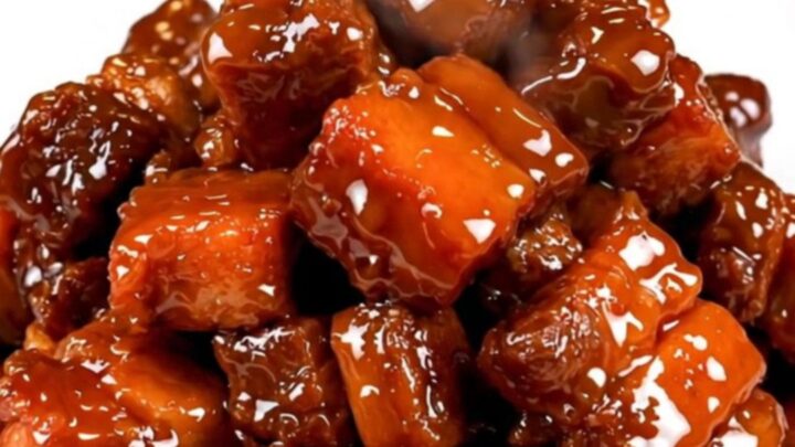 A plate of glossy, dark, and tender five-spice char siu pork chunks served on a white plate.