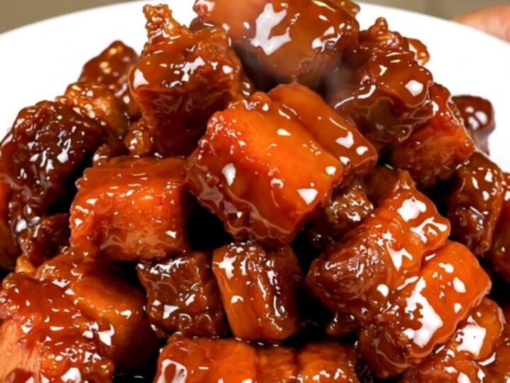 A plate of glossy, dark, and tender five-spice char siu pork chunks served on a white plate.