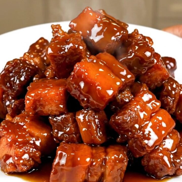 A plate of glossy, dark, and tender five-spice char siu pork chunks served on a white plate.