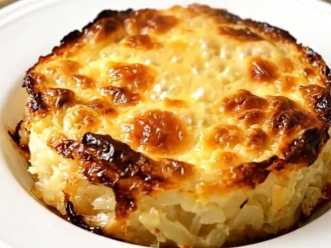 A steaming, golden Savoyard crozet gratin served on a plain white plate, showing a creamy and rich texture.